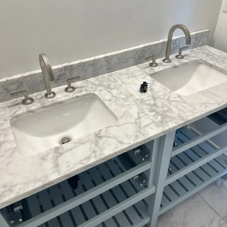 A bathroom with two sinks and marble counter tops.